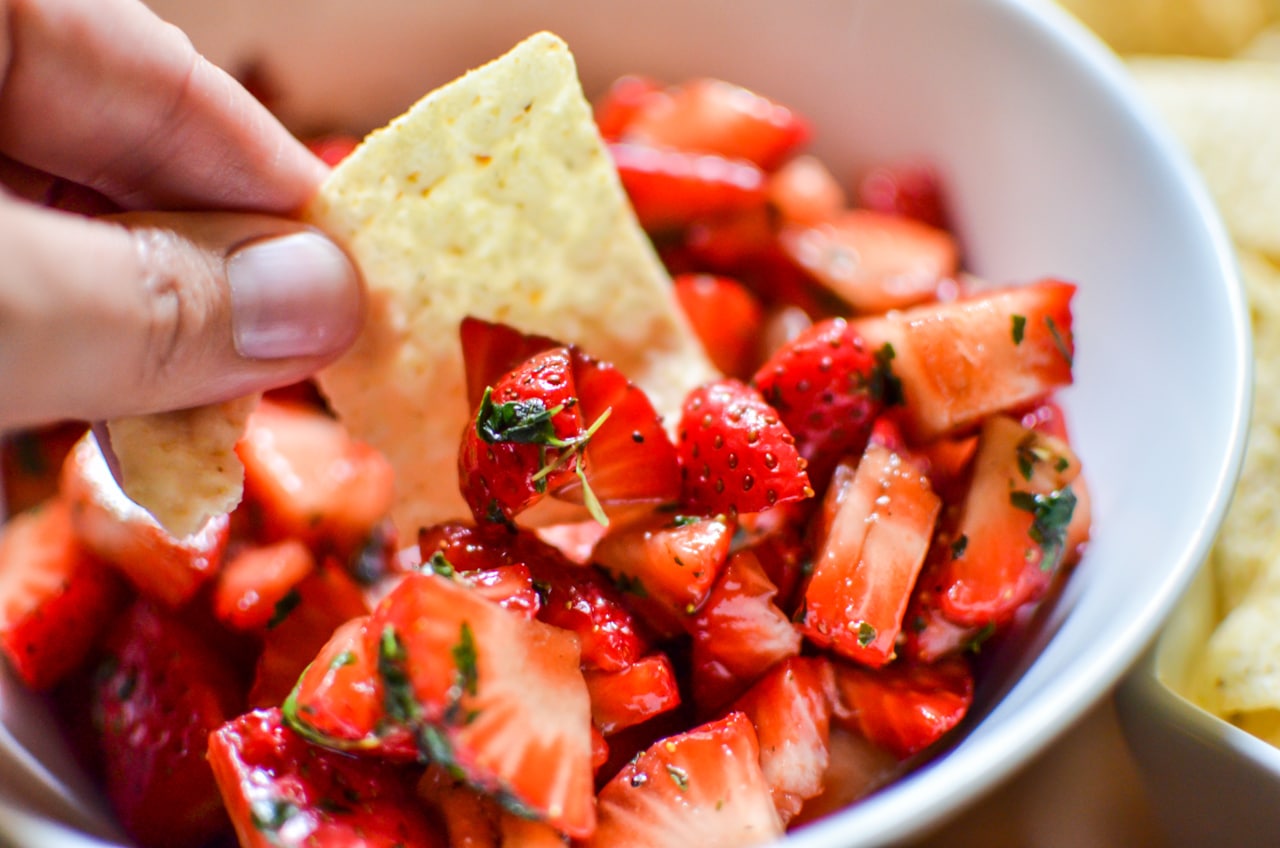 dipping tortilla chip into strawberry salsa