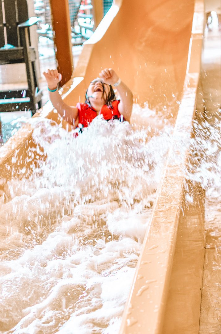 Check out Great Wolf Lodge tips for planning your next vacation. #greatwolflodge Girl excited and happy while coming down water slide at Great Wolf Lodge