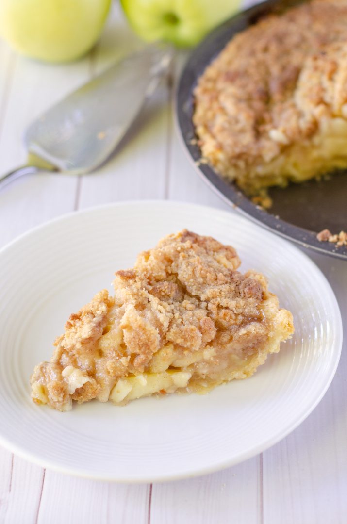 slice of apple crumble pie on white plate with pie server
